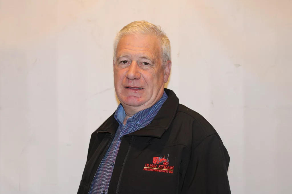 Man wearing a black jacket with the Irish Steam Preservation Society logo, smiling against a plain background.