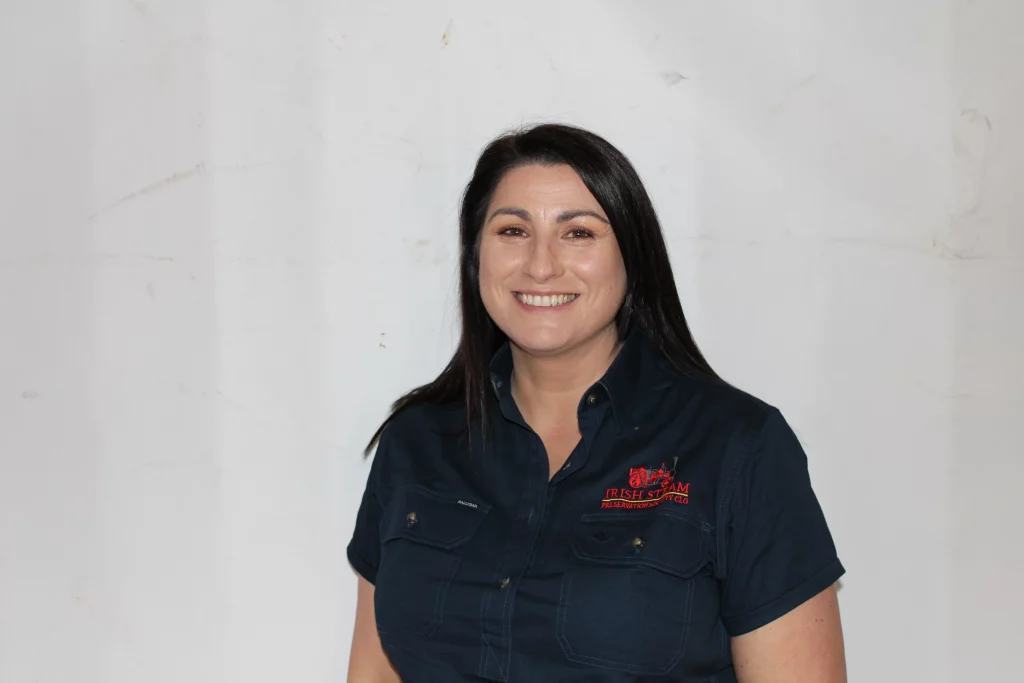 Smiling woman wearing a dark blue shirt with "Irish Steam Preservation Society" logo, posed against a neutral background.