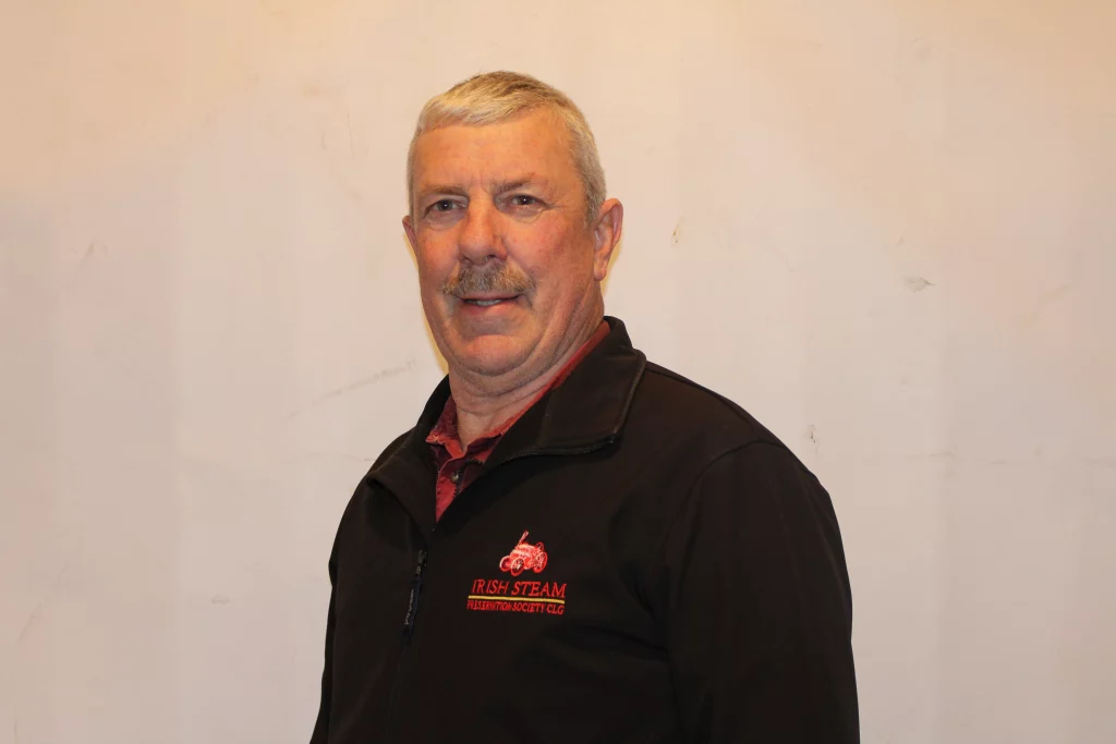 Man smiling in a dark jacket with the "Irish Steam Preservation Society" logo, set against a plain background.