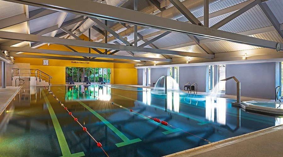 Indoor swimming pool at a the Midlands Park Hotel, featuring clear water, lane markings, and modern architectural design.