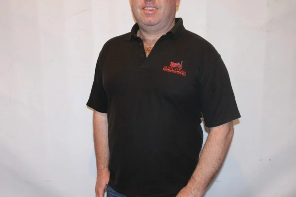 Man wearing a black polo shirt with "Irish Steam Preservation Society" logo against a plain background.