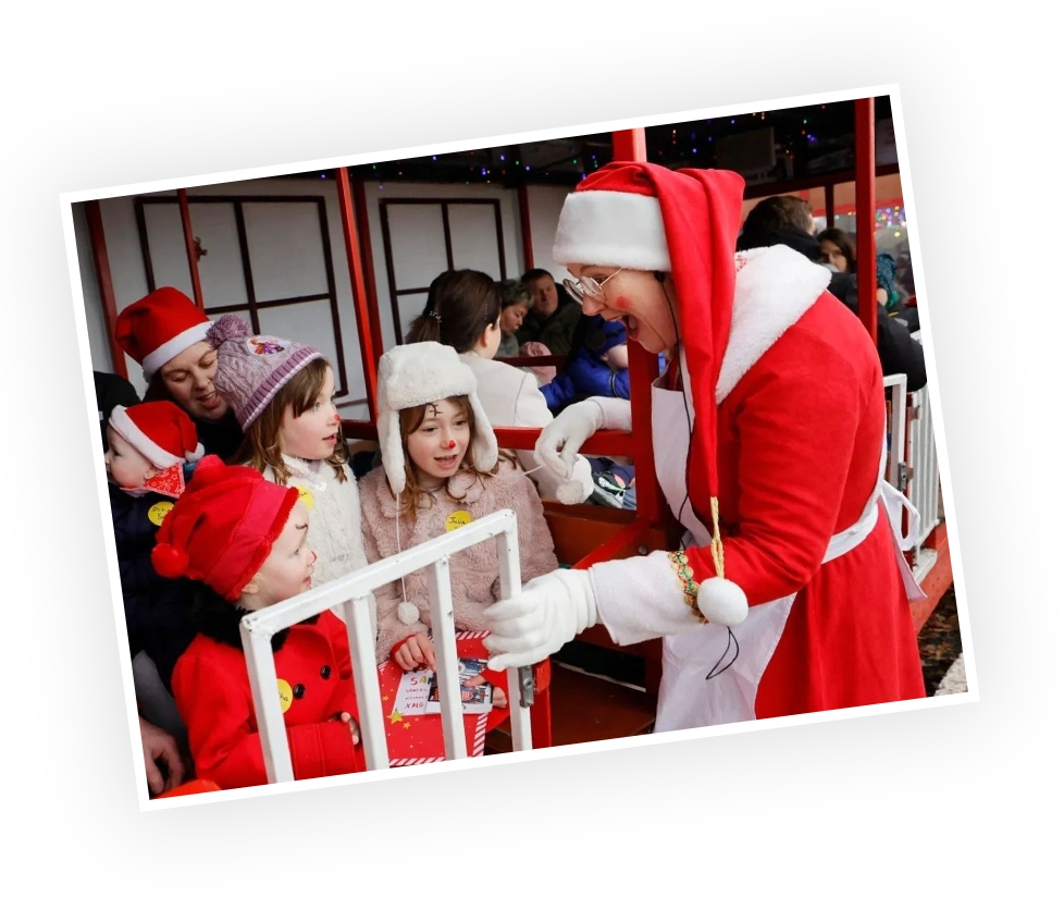 Children eagerly interacting with a character dressed as Santa Claus at a festive event, surrounded by a cheerful holiday atmosphere and decorations.