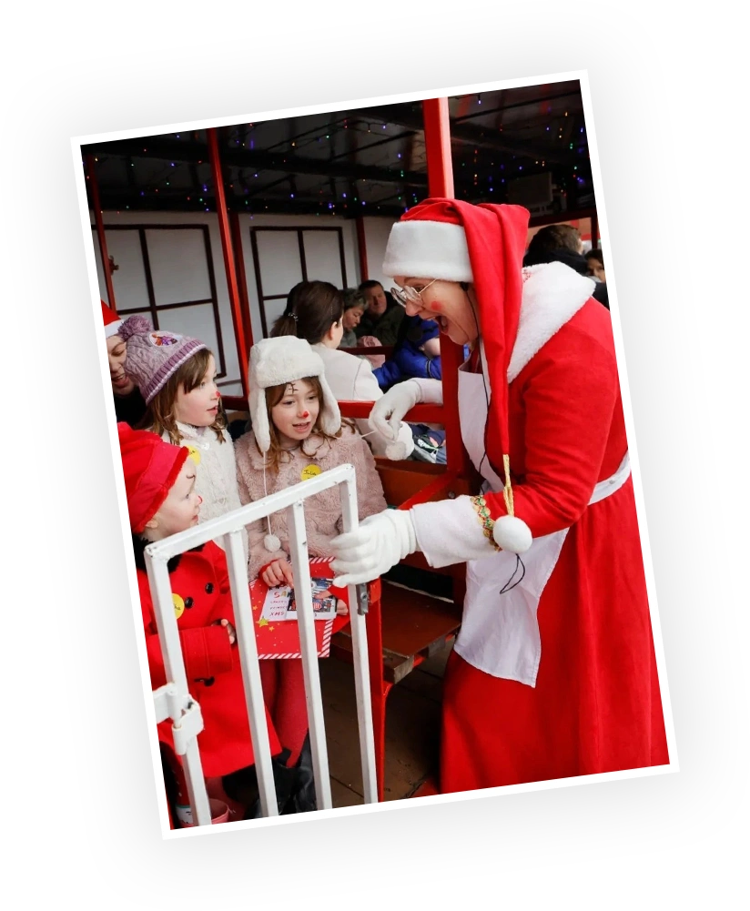 Children eagerly interacting with a character dressed as Santa Claus at a festive event, surrounded by a cheerful holiday atmosphere and decorations.